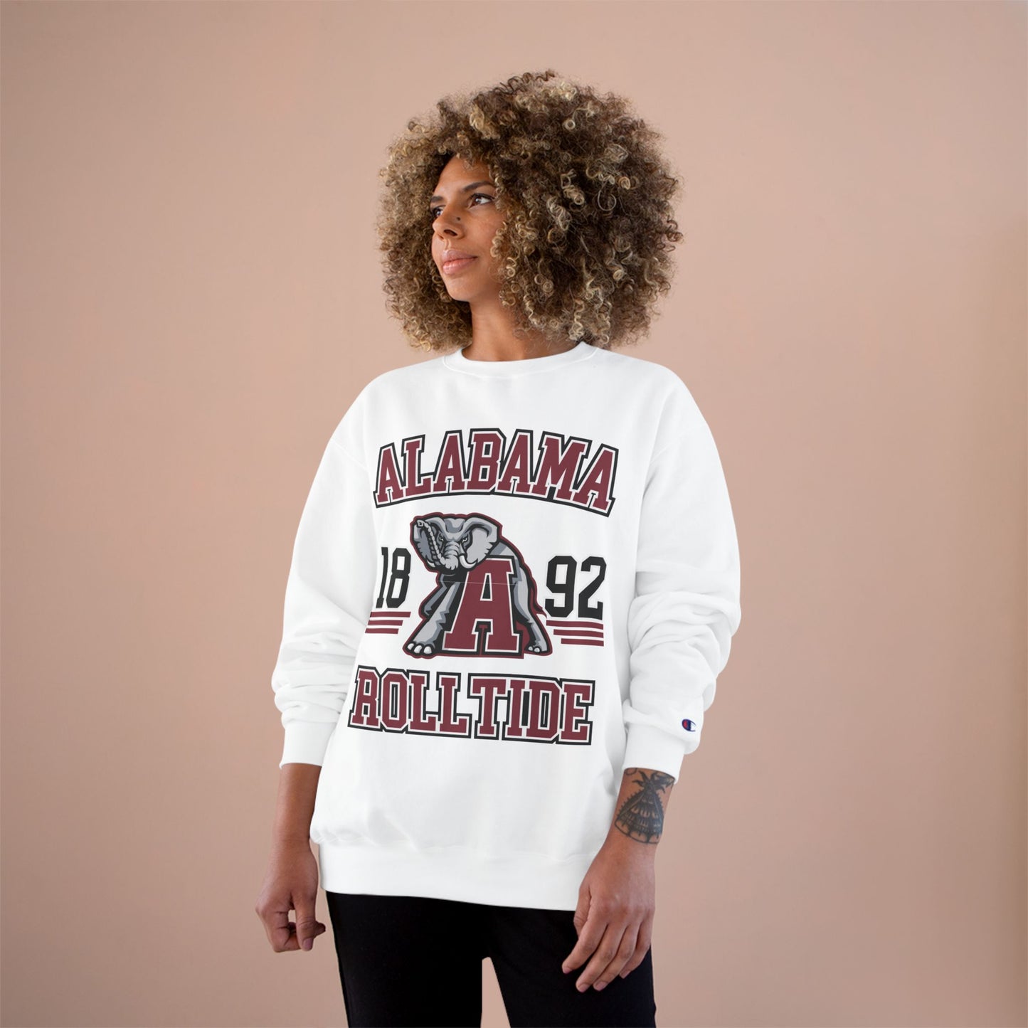 Person wearing a white 'Alabama Roll Tide' sweatshirt with an elephant graphic on a beige background