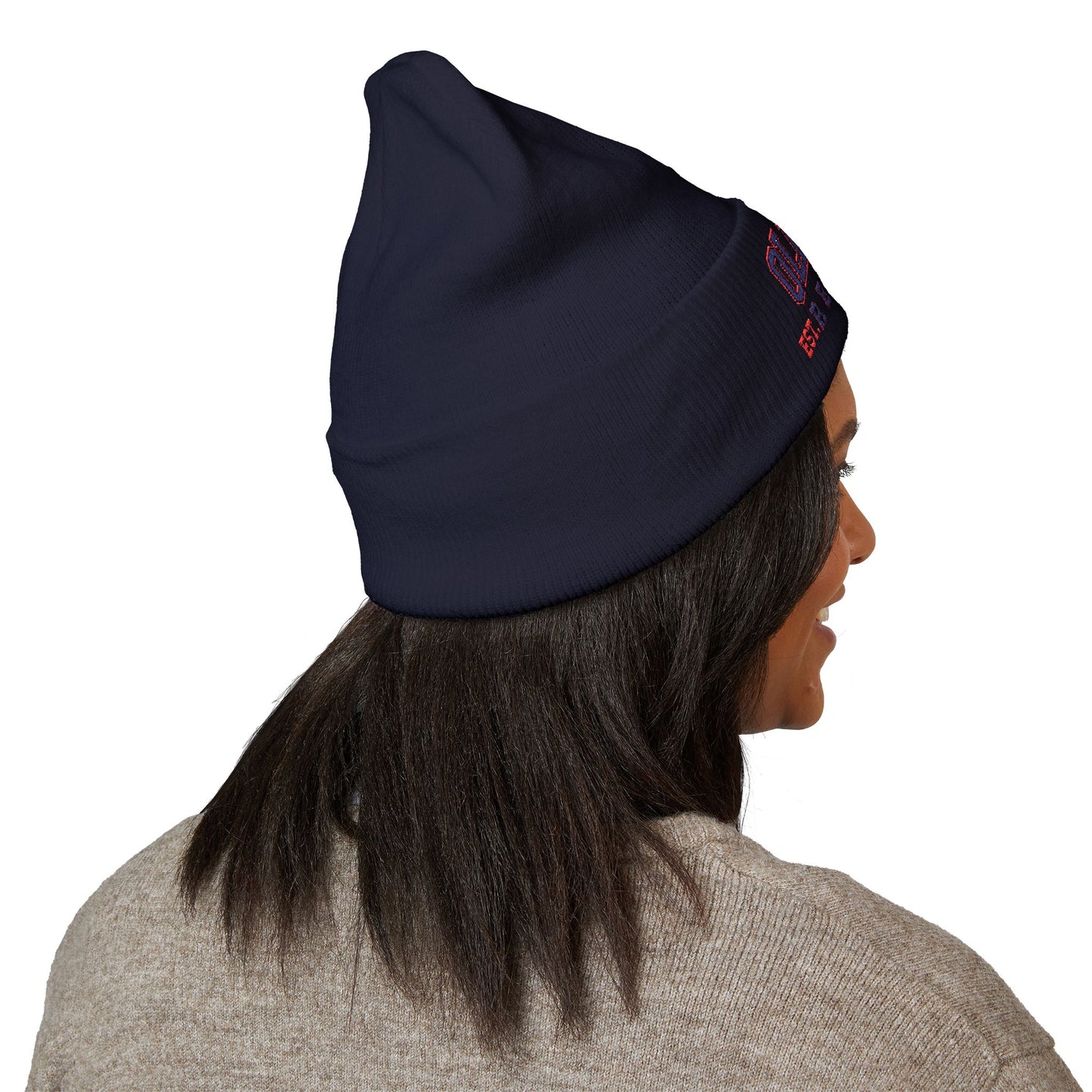 Person wearing a navy beanie with a ole miss logo on a white background